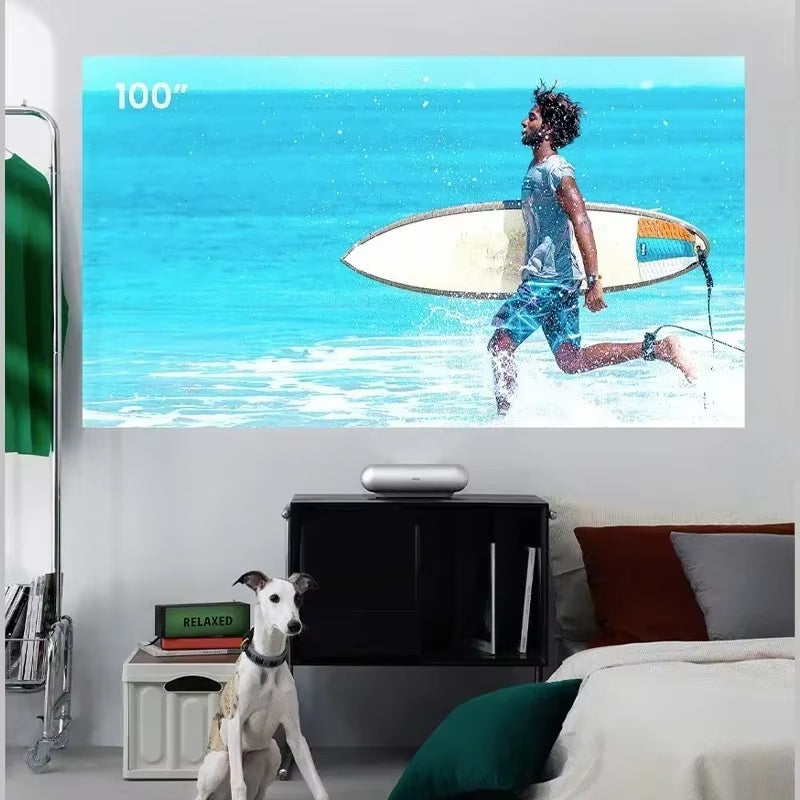 JMGO O1S Ultra Short Focus Projector projecting a 100-inch image of a man with a surfboard in his hand in the water, showcasing its large screen size and vibrant image quality.